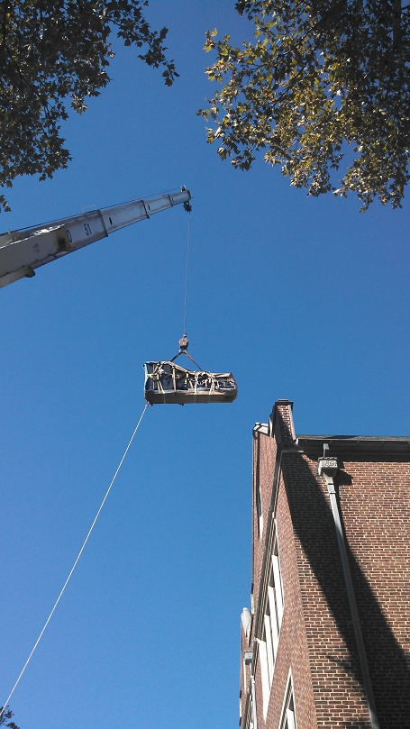 piano hanging from high crane